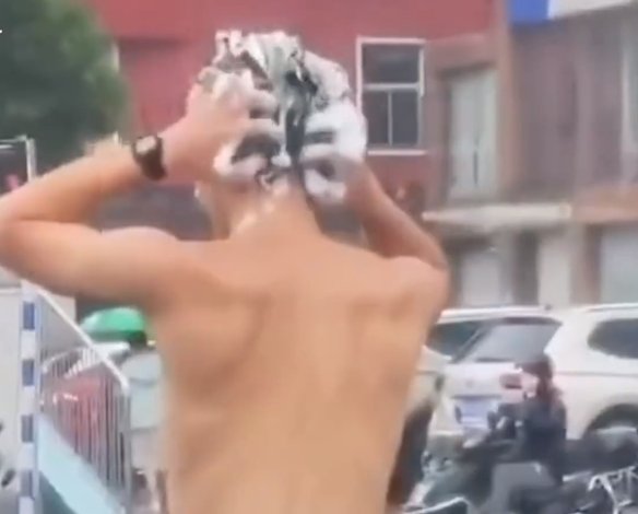 江苏一男子雨天骑摩托等红灯时洗头，此举是否违法？